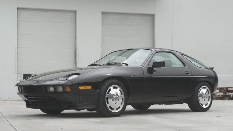 A 1986 Porsche 928 S parked by a white building