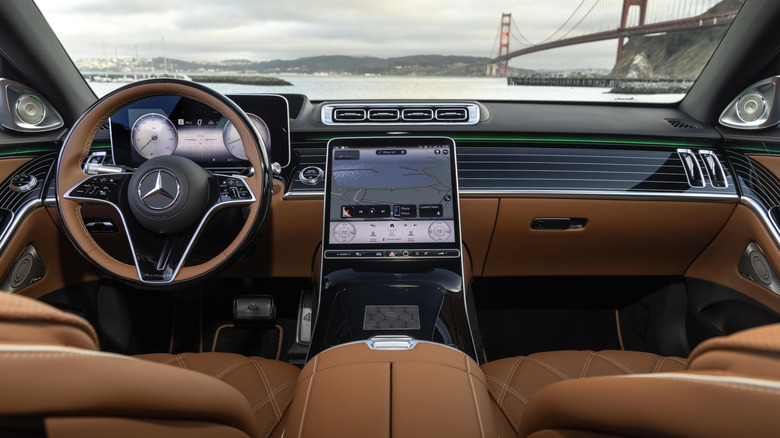 A wide shot of the dash in the 2026 Mercedes-Maybach S680 with a dark brown interior and a view of the Golden Gate Bridge out the windshield on a gray day