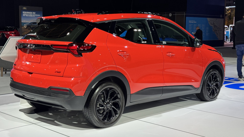 Rear three-quarters shot of a red 2027 Chevrolet Bolt on the show floor at the LA Auto Show