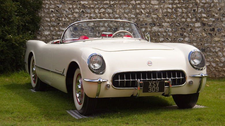 A white 1953 Chevrolet Corvette convertible at the Goodwood Festival of speed, parket in front of a stone wall and sitting on grass