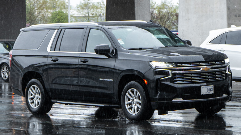 A black Chevrolet Suburban on a rainy city street.