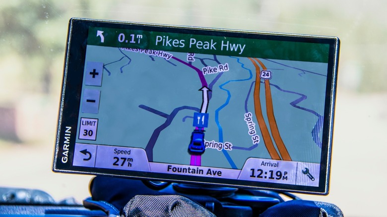 An up-close image of a Garmin GPS system installed on a car dash and showing the vehicle's speed