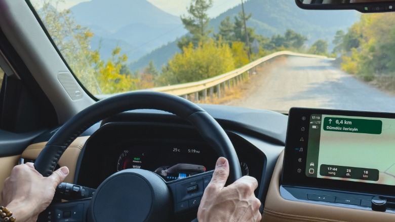 A person driving on a mountain road with a GPS active on on the dash