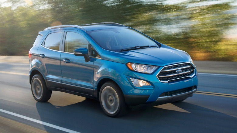 Front three-quarters shot of a blue Ford EcoSport driving past blurry trees