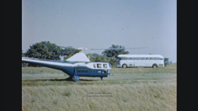 The helicopter bus and one of Greyhound's buses parked on the grass of one of its Highway Transfer Stations.