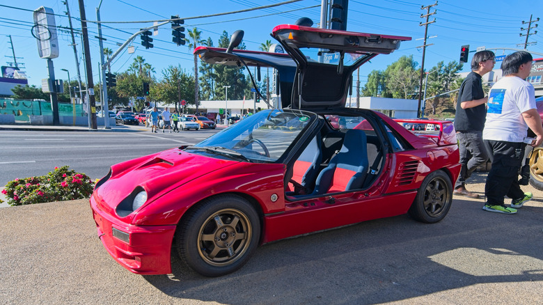 A red Autozam AZ-1 mid-engined sportscar with gullwing doors