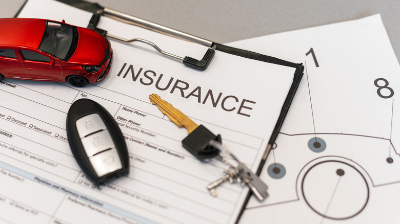 A desk with an insurance form, keys, and a toy car on top of it