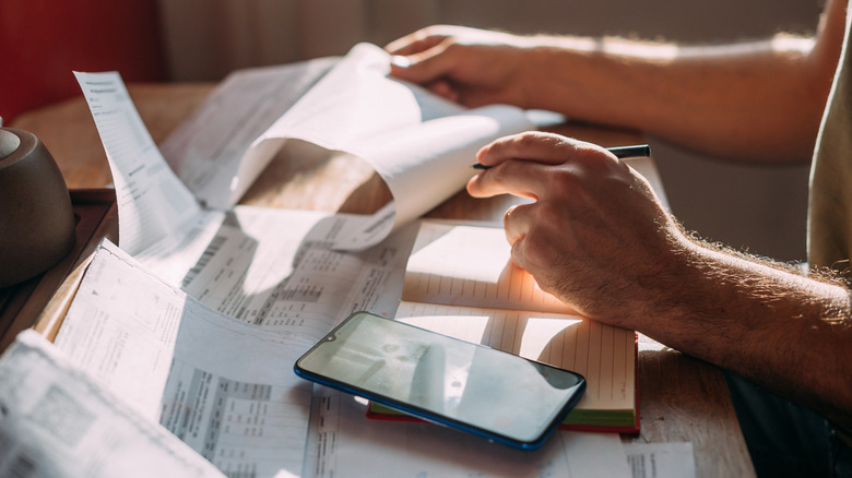 A man at a desk adding up numbers from numerous bills