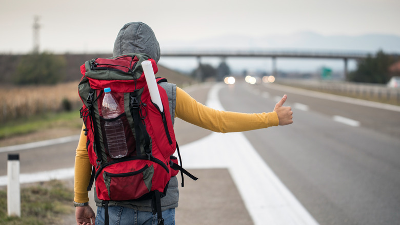 Hitchhiker with thumbs up, trying to stop a car for a free ride