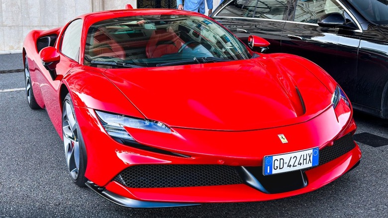 A red Ferrari SF90 Stradale parked next to a black car