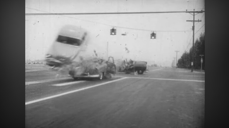 A car runs a red light and stuntman Joie Chitwood's car hits it and flies into the air over the intersection.