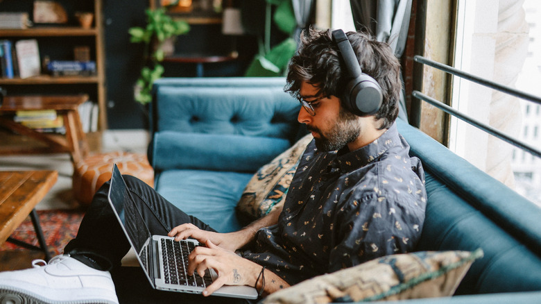 Working on a laptop while listening to music on the couch