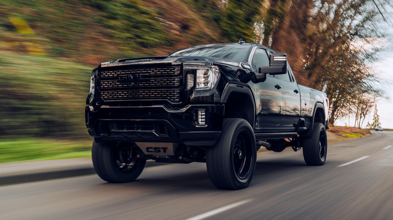 Large lifted diesel GMC pickup truck driving down the road
