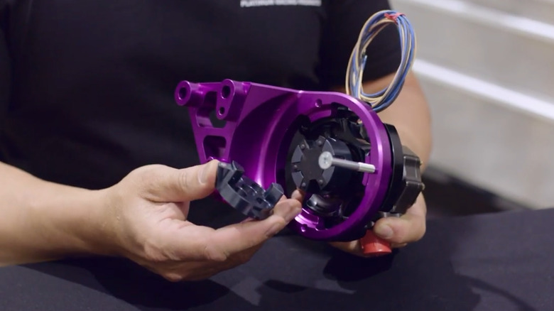 A close up of technician's hands holding parts of a mechanical fuel pump