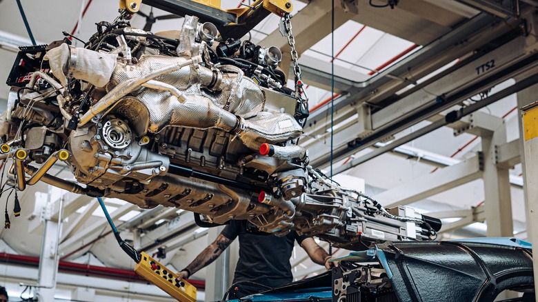 A Lamborghini V12 engine being maneuvered on the assembly line
