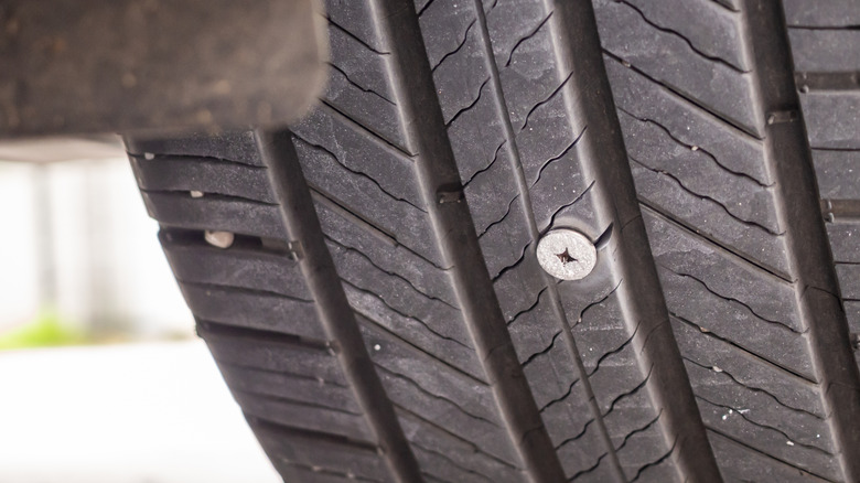 A car tire punctured by a metal screw