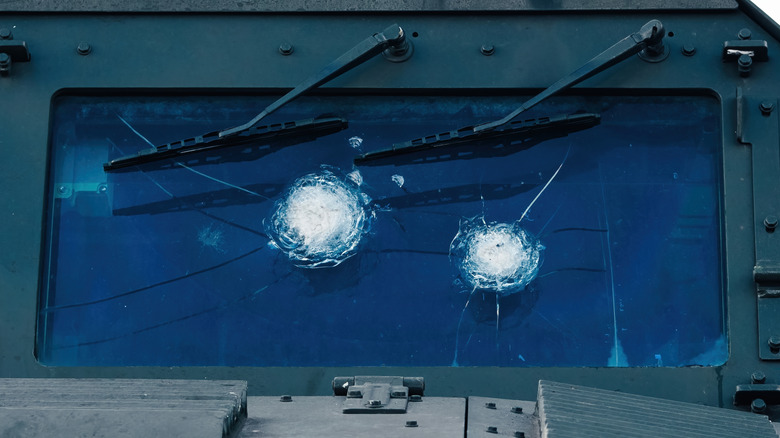 An image of an armored vehicle's front windshield bulletproof glass that has been damaged by artillery fire.