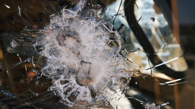 A close-up image of an armored vehicle's bulletproof window glass that has successfully stopped gunfire.