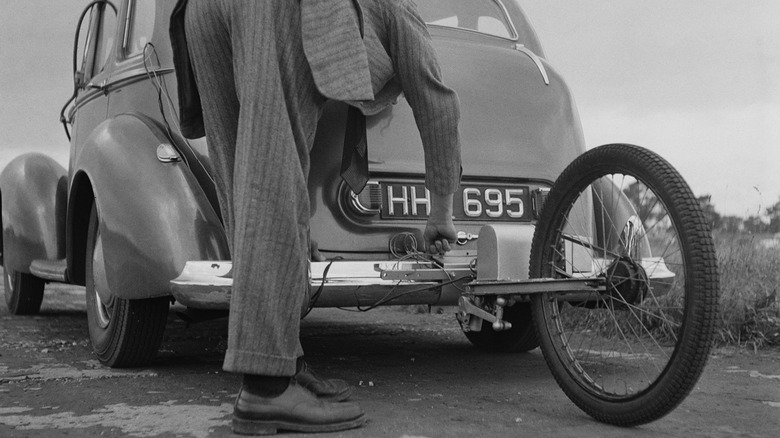 Man attaching fifth-wheel test rig to back off old car