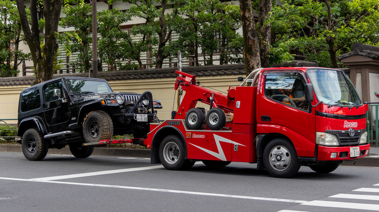 A tow truck driving away with a repossessed car