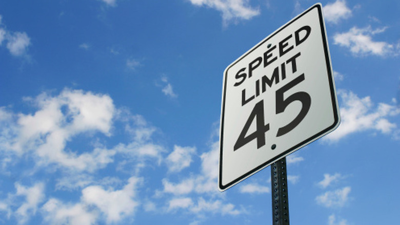 A 45 mph speed limit sign against a blue sky with small white clouds