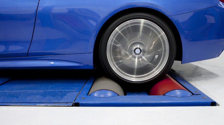A blue sports car being tested on a dynamometer.