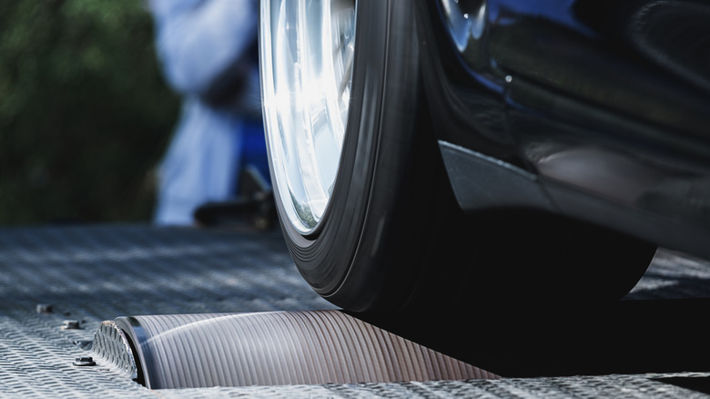 A car's tire being spun on a rolling dynamometer.