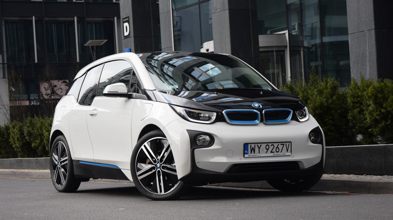 A white BMW i3 parked in front of a glass building