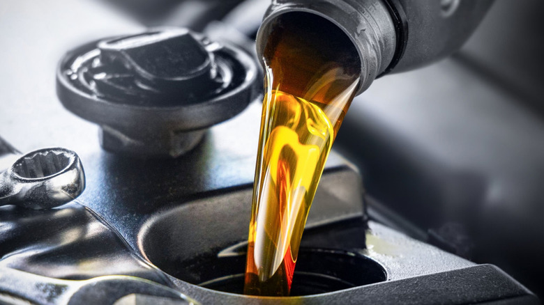 Close up shot of pouring fresh motor oil into an engine