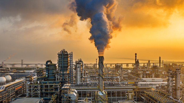 Oil refinery at sunset with smoking chimney