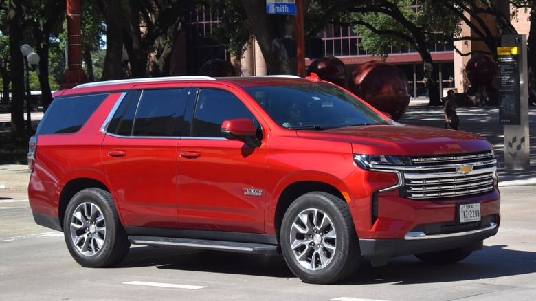 A front-end shot of a 2021 red Chevrolet Tahoe SUV parked in front of a Chevrolet dealership.