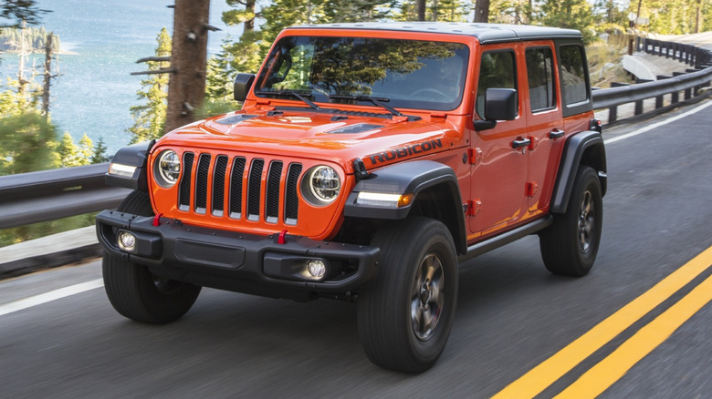 Jeep Wrangler Rubicon driving on a paved road with a body of water in the background