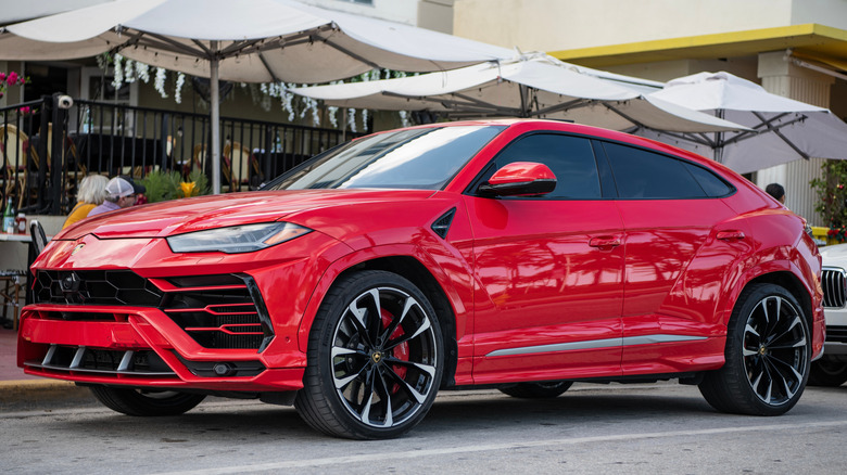 A red Lamborghini Urus parked on a city street