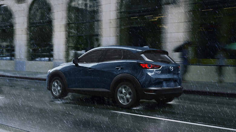 A blue 2020 Mazda CX-3 in front of a building in the rain.