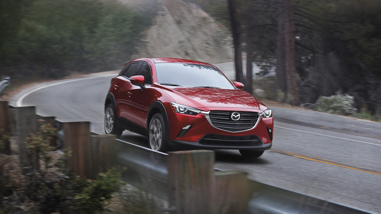 A red 2020 Mazda CX-3 on a two-lane road.