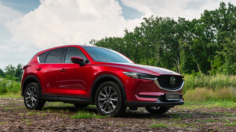 A red Mazda CX-5 on an unpaved trail.