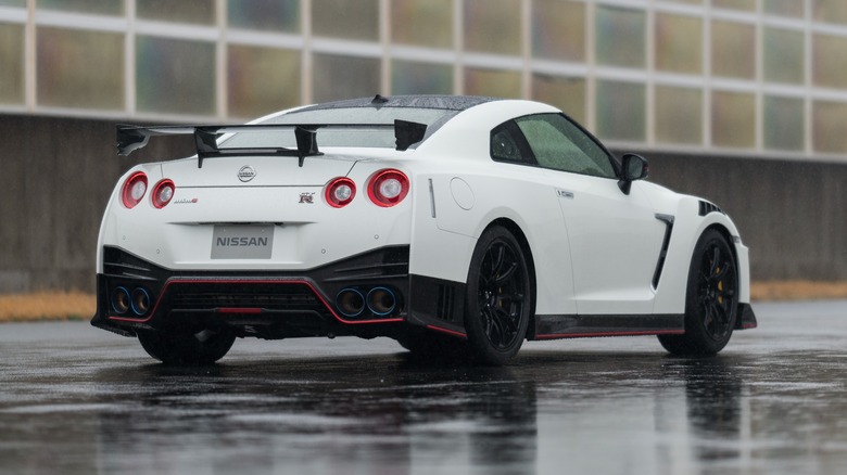 Rear view of a white 2020 Nissan GT-R on a wet track.