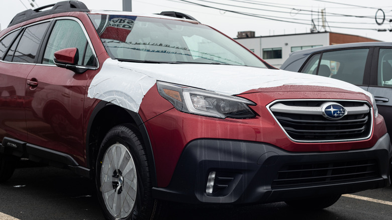 Red Subaru Outback extracurricular a dealership.