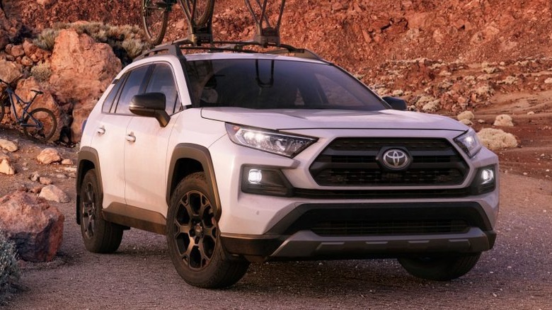 A white 2020 Toyota RAV4 parked near a rocky hill.