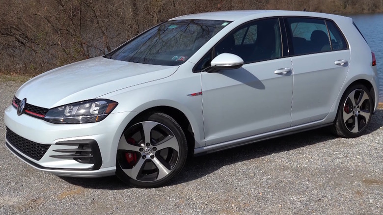 A white 2020 Volkswagen Golf GTI in front of a lake.