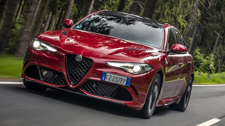 The Alfa Romeo Giulia Quadrifoglio driving along a paved road in a dense forest