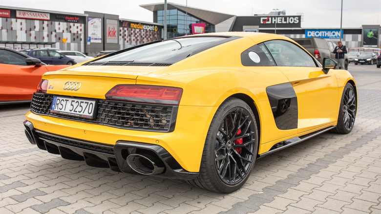 A yellow Audi R8 RWD rear three-quarter view on a public car park.