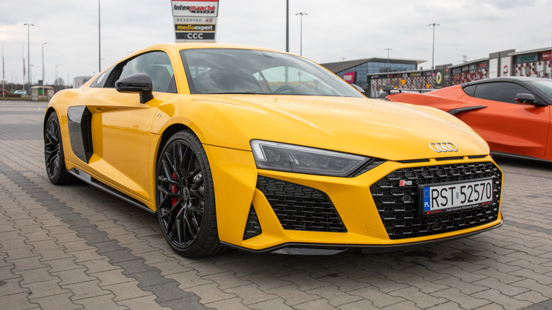 A yellow V10 Audi R8 sports car parked outside.
