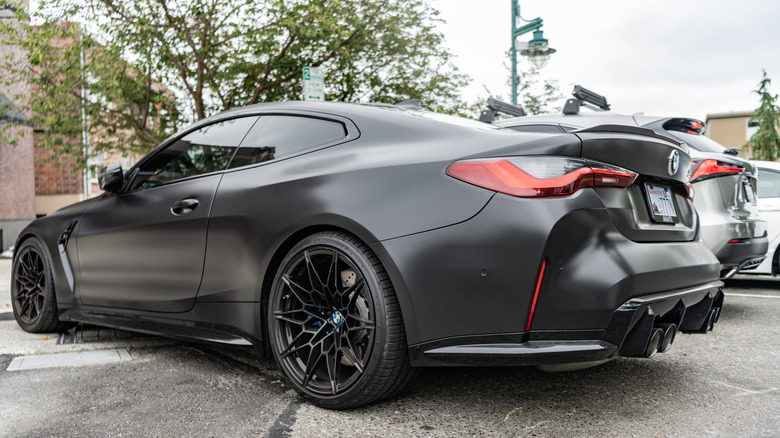 A rear three-quarter view of a satin black G82 BMW M4 Coupe