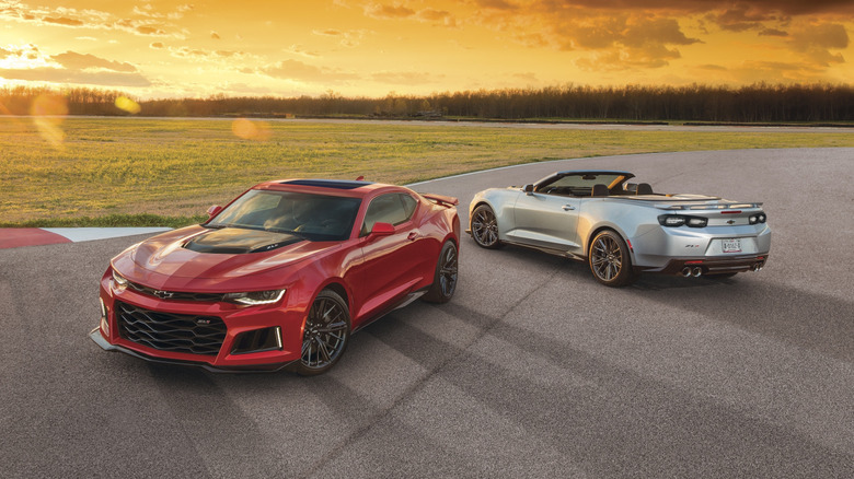 A red 2021 Chevrolet Camaro ZL1 coupe and 2021 Chevrolet Camaro ZL1 convertible on pavement.