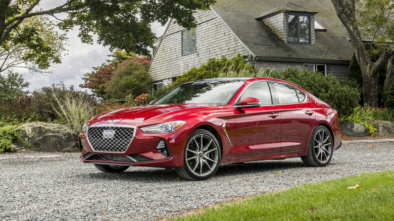A red 2021 Genesis G70 on a gravel driveway.