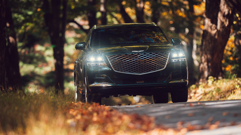 A 2021 black Genesis GV80 on an autumn road.