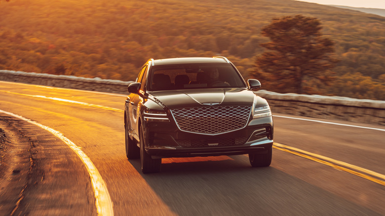 A 2021 Genesis GV80 on a roadway at sunset
