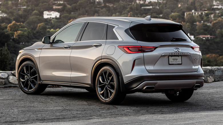 A silver 2021 Infiniti QX50 parked at the edge of a parking lot.
