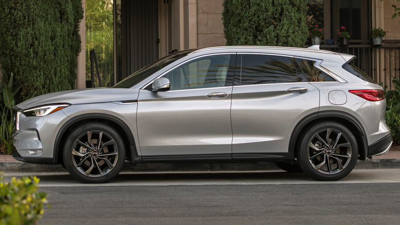 A silver second-gen Infiniti QX50 parked in front of a building